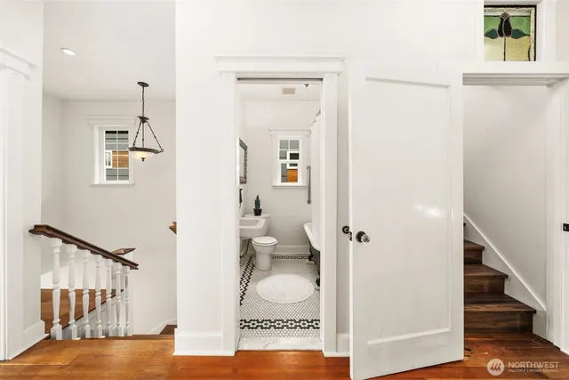 a view of a hallway with bathroom and wooden floor