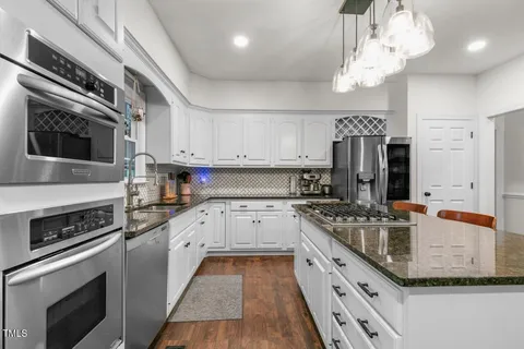 a kitchen with stainless steel appliances granite countertop a stove and a wooden floors