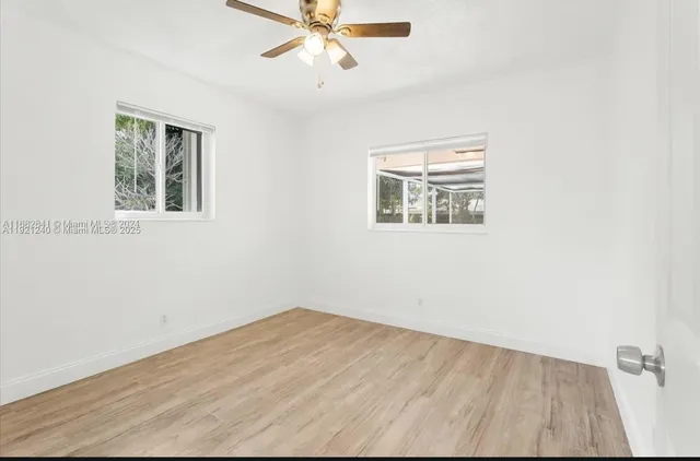 an empty room with a window and a ceiling fan