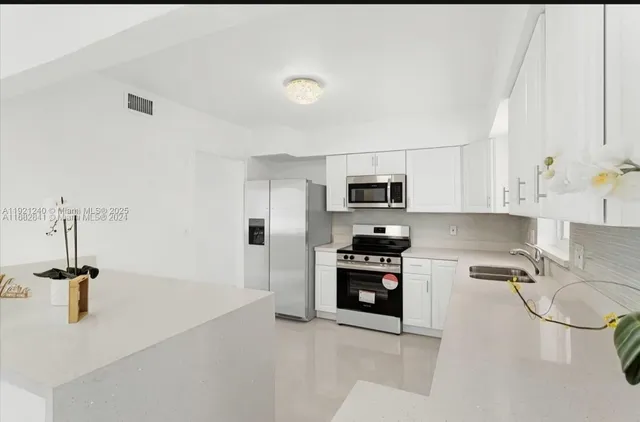 a kitchen with stainless steel appliances granite countertop a sink dishwasher a stove and a refrigerator with wooden floor