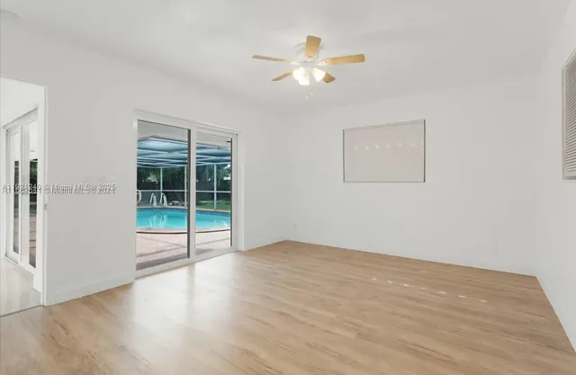a view of an empty room with glass door and wooden floor