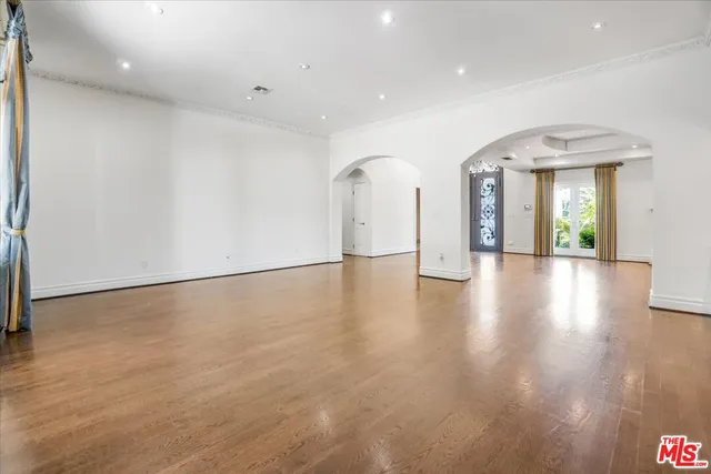 an empty room with wooden floor fireplace and windows