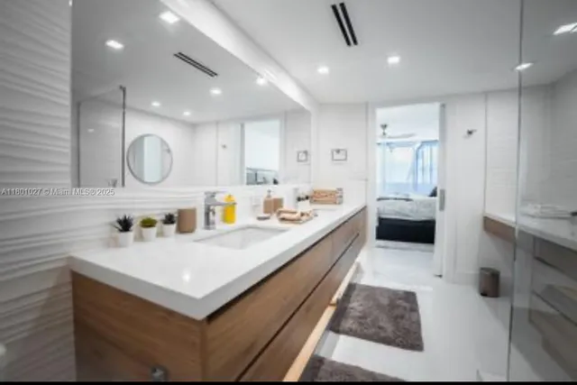 a large white kitchen with a white countertops a sink and stainless steel appliances