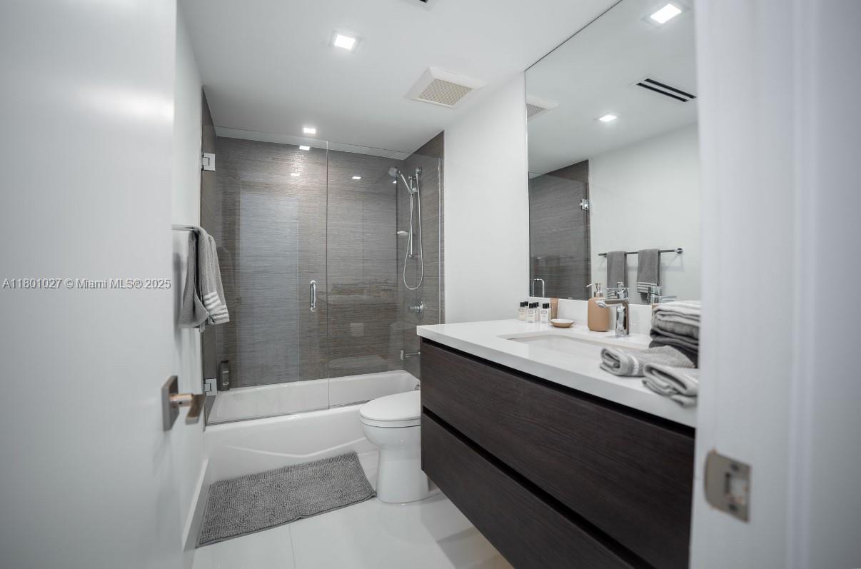 5600 Collins Avenue, Unit 14K Miami Beach, FL 33140 - Photo 19 of 27 a bathroom with a double vanity sink toilet mirror and bathtub