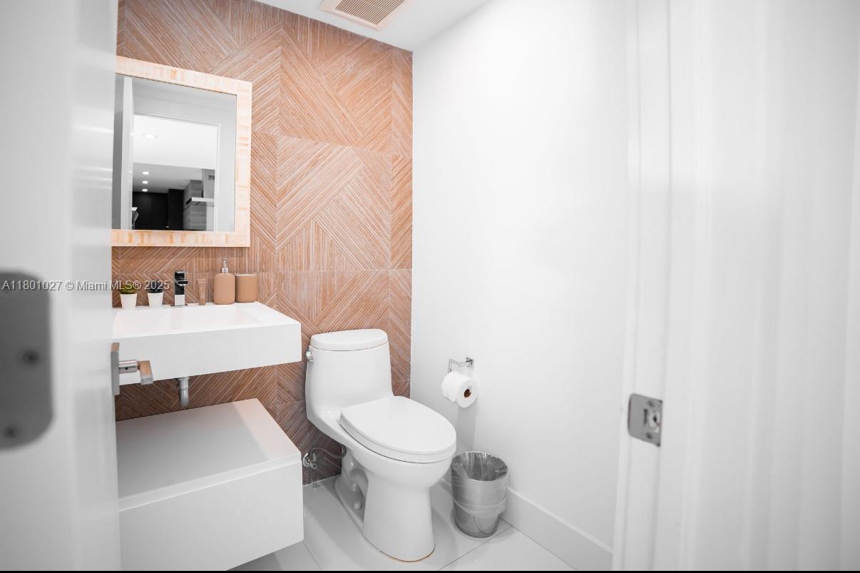 5600 Collins Avenue, Unit 14K Miami Beach, FL 33140 - Photo 20 of 27 a bathroom with a sink toilet and mirror