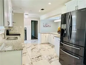 a kitchen with granite countertop a refrigerator and a sink
