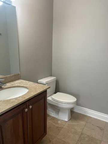 a bathroom with a granite countertop toilet and a sink