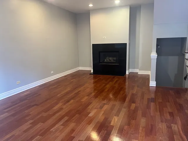 a view of an empty room with wooden floor and a fireplace