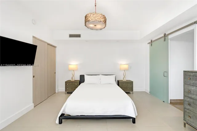 a bedroom with a bed and a flat tv screen on dresser