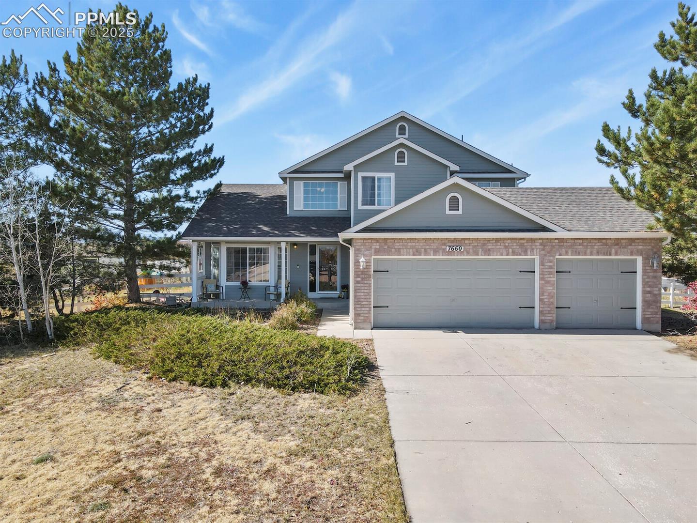 7660 Bullet Road Peyton, CO 80831 - Photo 42 of 50 View of front of home featuring brick siding, covered porch, driveway, an attached garage, and roof with shingles