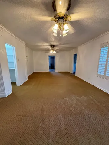 a view of an empty room with a chandelier fan