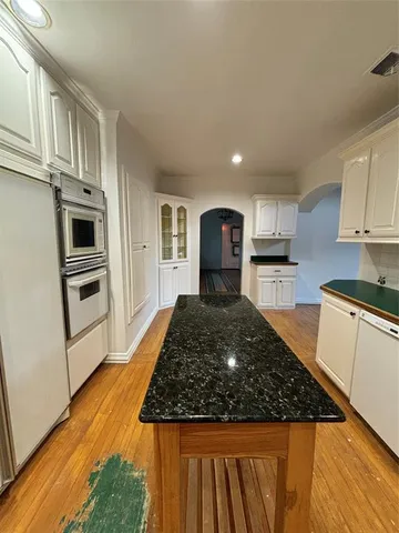 a large kitchen with cabinets appliances and wooden floor