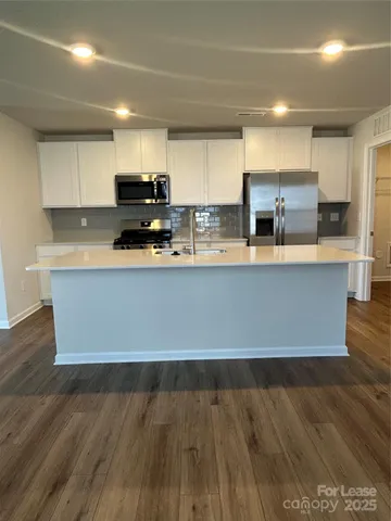 a large kitchen with stainless steel appliances a large counter top a stove and a refrigerator