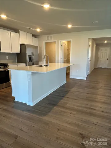 a large kitchen with stainless steel appliances a large counter top a stove and a refrigerator