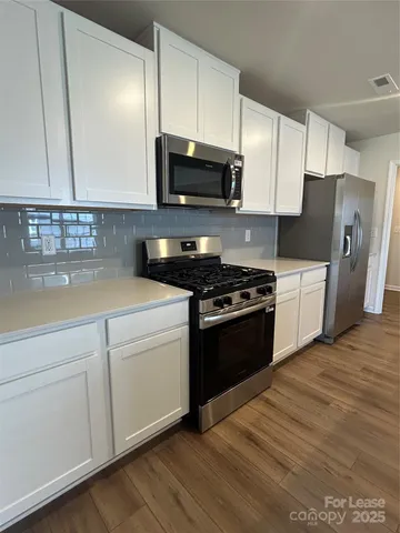 a kitchen with stainless steel appliances granite countertop a stove a sink and a microwave