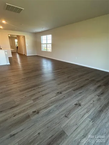 a view of empty room with wooden floor and window