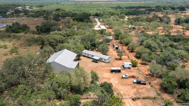 an aerial view of residential house with outdoor space and trees all around