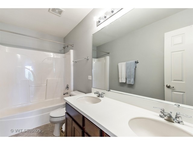 3153 Riley Road Montgomery, IL 60538 - Photo 13 of 15 a bathroom with a sink a toilet a mirror and bathtub