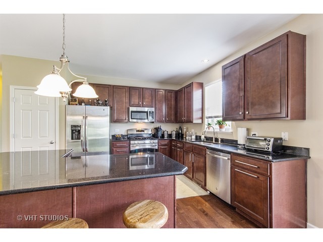 3153 Riley Road Montgomery, IL 60538 - Photo 4 of 15 a kitchen with stainless steel appliances granite countertop wooden cabinets a stove a sink a dining table and chairs
