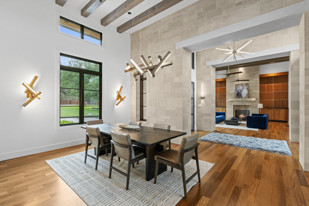 1905 Paisano Road Austin, TX 78746 - Photo 6 of 40 An inviting dining room with towering ceilings flows into a cozy living area featuring a modern fireplace.