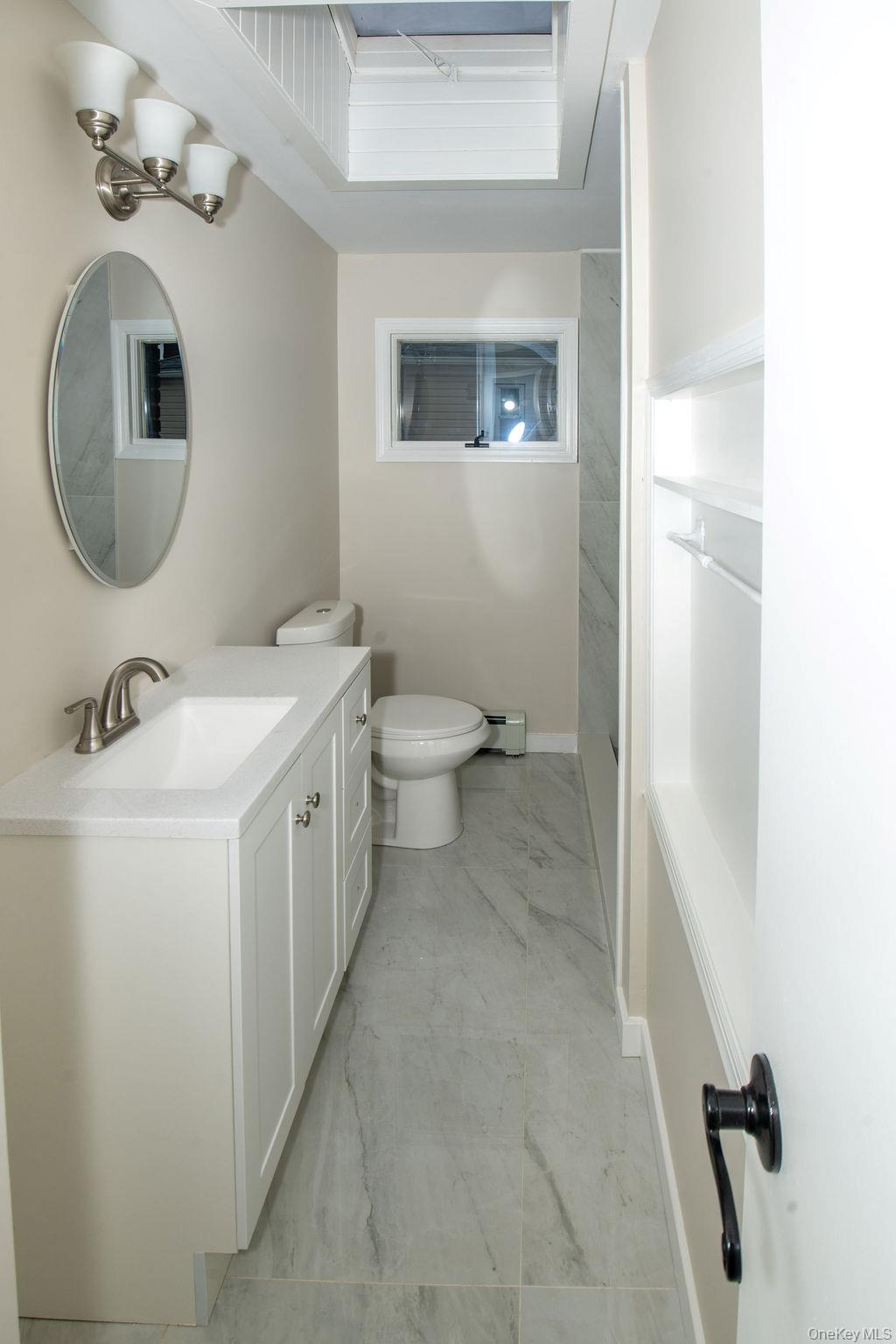 15 East Clearwater Road Lindenhurst, NY 11757 - Photo 12 of 25 a bathroom with a sink a toilet and mirror