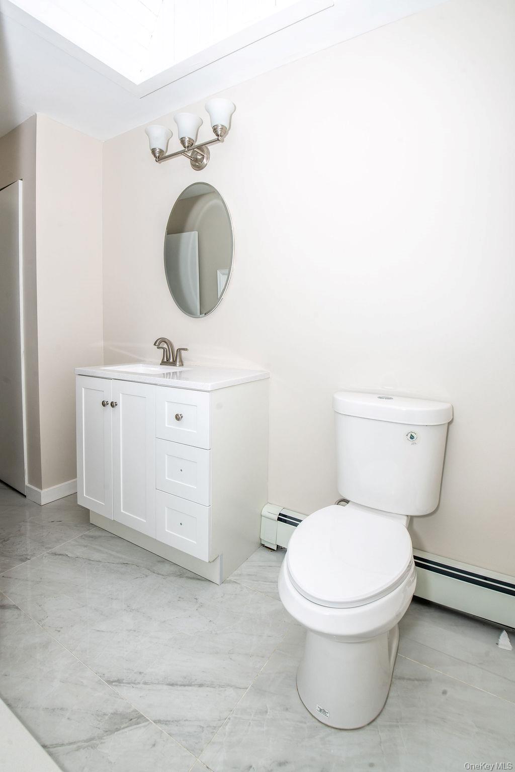 15 East Clearwater Road Lindenhurst, NY 11757 - Photo 14 of 25 a bathroom with a toilet sink vanity and mirror