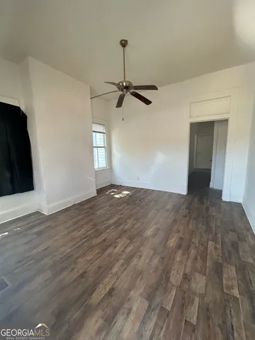 a view of empty room with wooden floor and ceiling fan