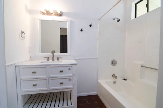 a bathroom with a bathtub sink vanity and mirror