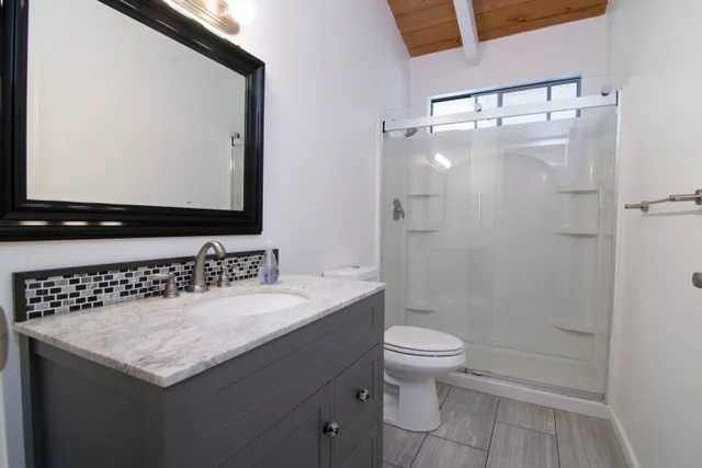 a bathroom with a granite countertop sink toilet and shower