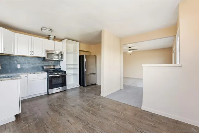 a kitchen with granite countertop a refrigerator and a stove top oven