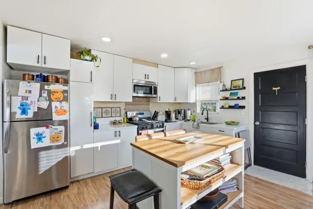 a kitchen with a refrigerator a stove a sink and wooden floor