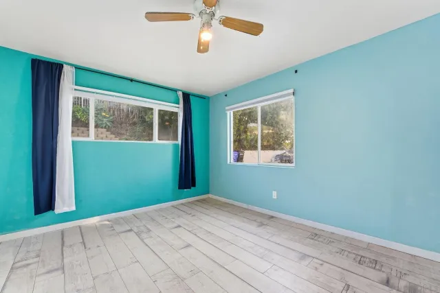 a view of empty room with window and ceiling fan