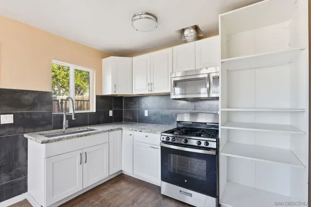 a kitchen with granite countertop white cabinets and appliances
