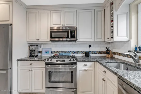 a kitchen with granite countertop white cabinets sink and stainless steel appliances