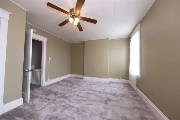 an empty room with closet and a ceiling fan