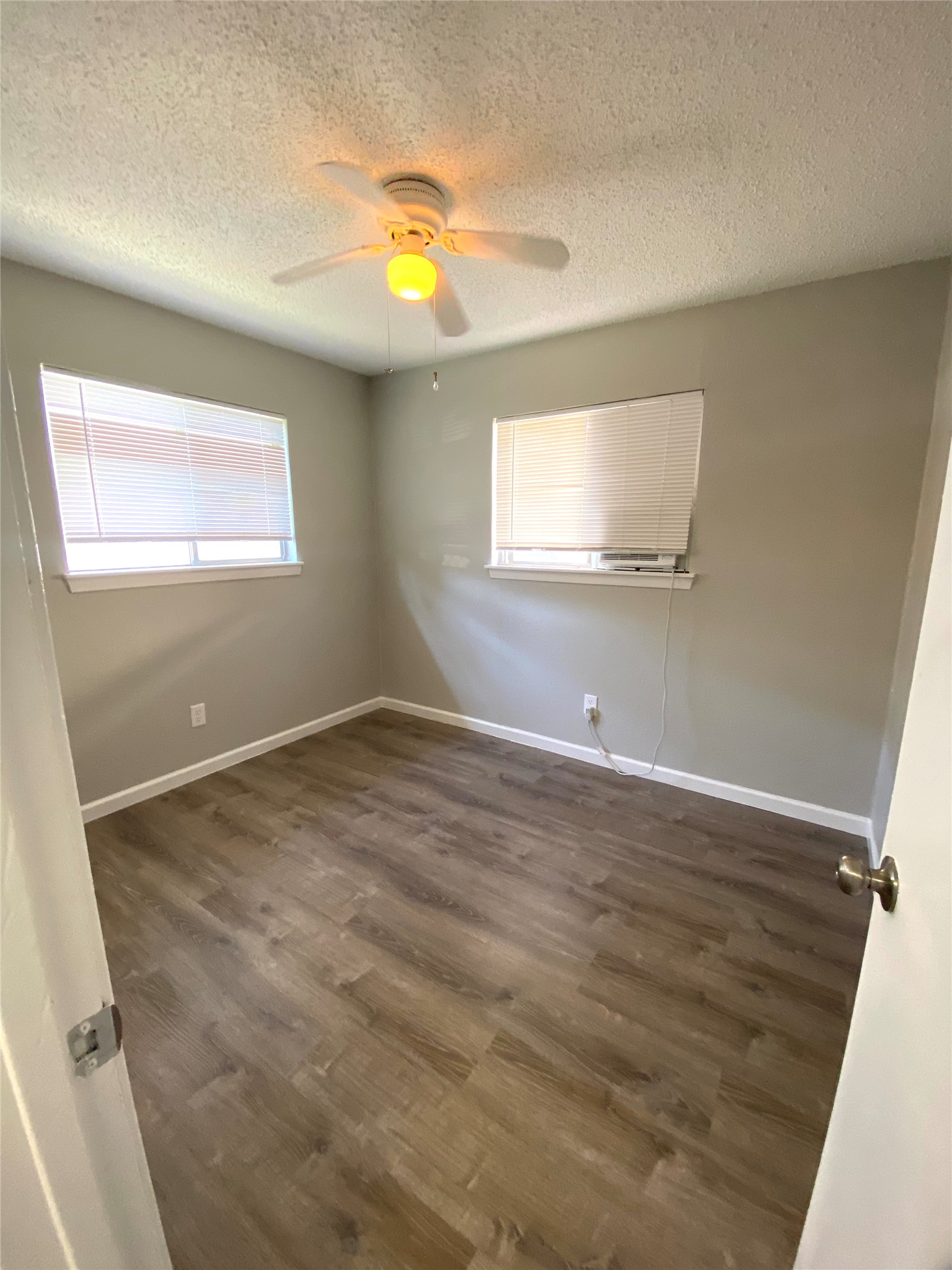 404 Swanee Drive, Unit B Austin, TX 78752 - Photo 4 of 5 Empty room with a textured ceiling, dark wood-style flooring, and a ceiling fan