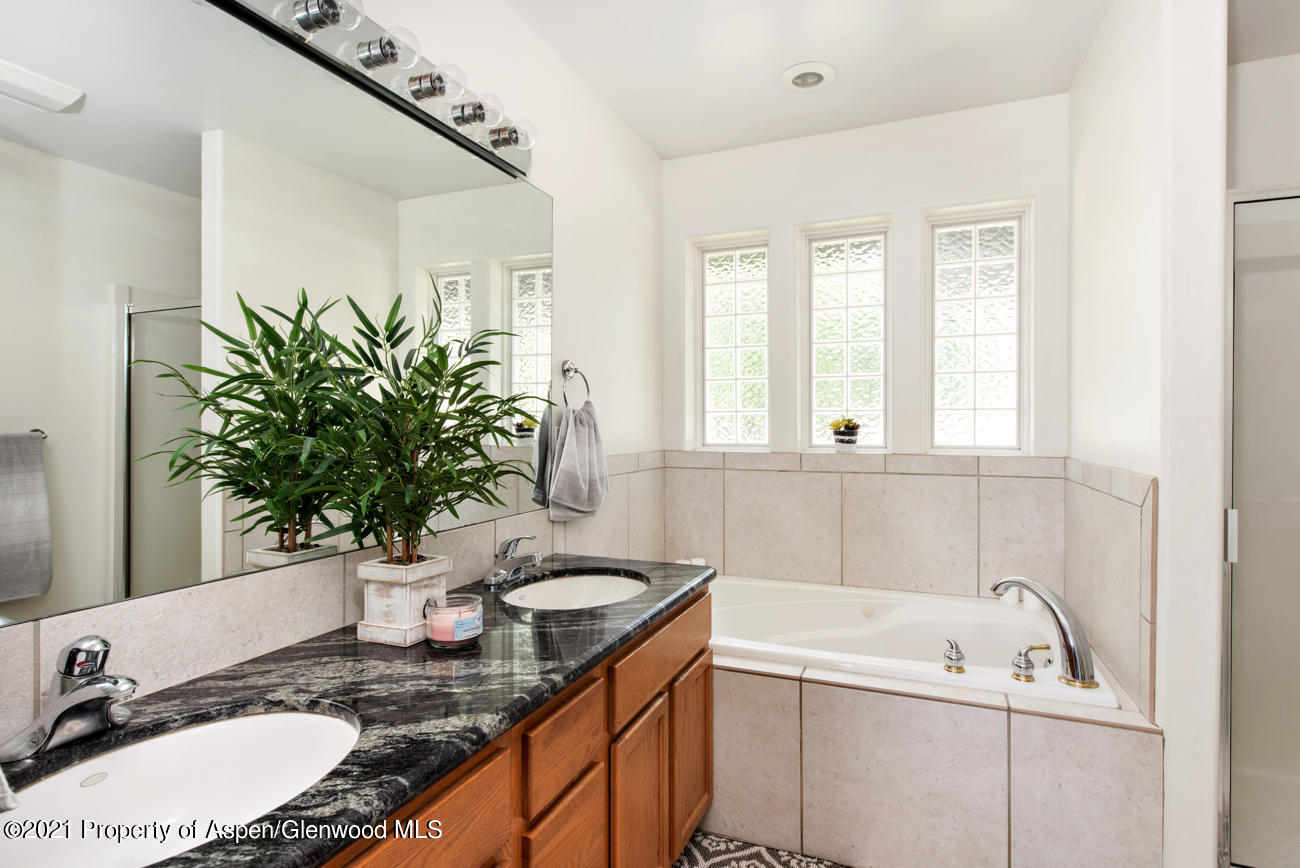 1090 Hickory Drive Rifle, CO 81650 - Photo 9 of 27 a bathroom with a granite countertop sink a mirror and a bathtub