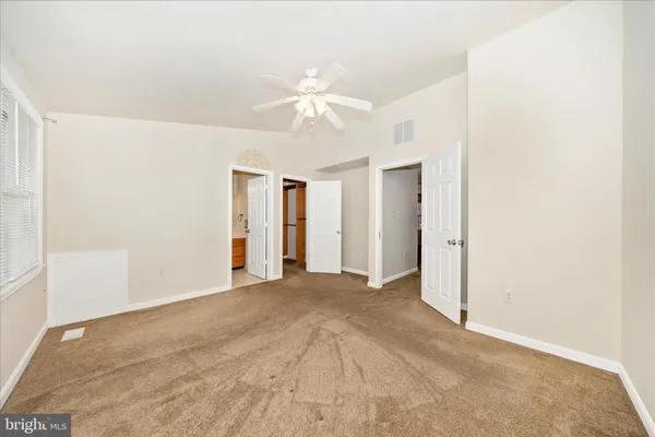 an empty room with windows and fan