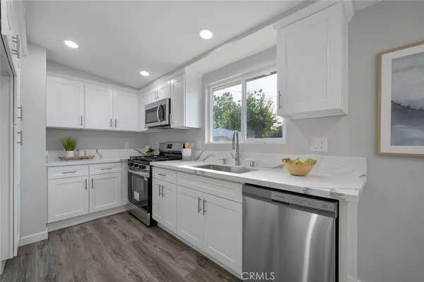 a kitchen with a sink white cabinets and white appliances