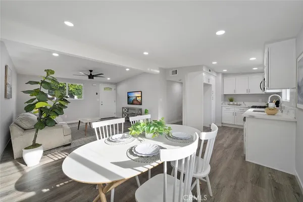 a view of a dining room with furniture a kitchen and wooden floor