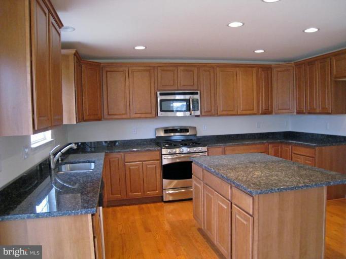 8012 Clark Station Road Severn, MD 21144 - Photo 6 of 8 a kitchen with stainless steel appliances granite countertop a stove a sink and a microwave