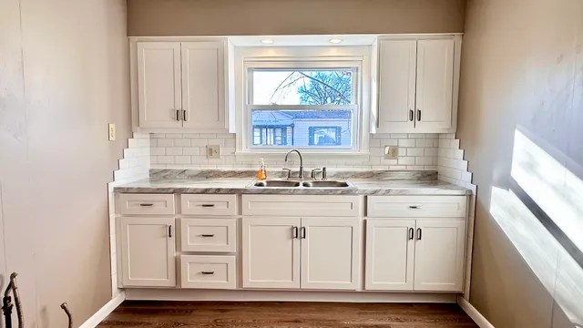 a kitchen with granite countertop white cabinets and a sink