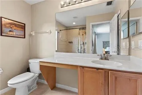 a bathroom with a granite countertop toilet sink and mirror