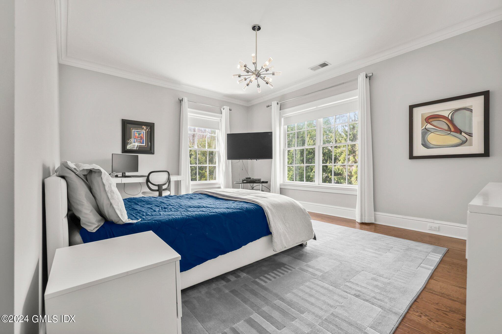 6 Coachlamp Lane Greenwich, CT 06830 - Photo 20 of 33 a spacious bedroom with a large bed a chandelier and windows