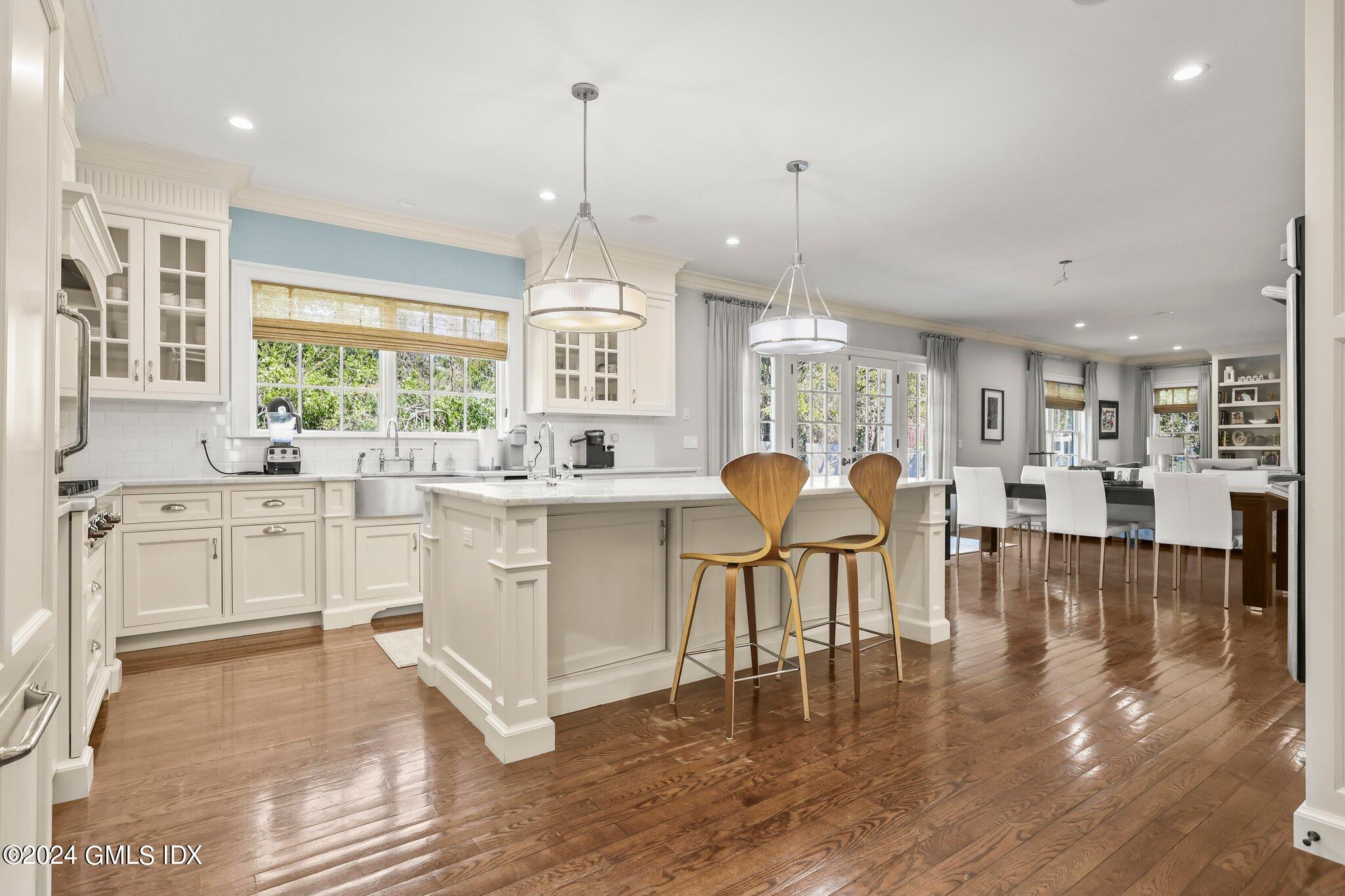 6 Coachlamp Lane Greenwich, CT 06830 - Photo 9 of 33 a kitchen with stainless steel appliances granite countertop a stove top oven a sink a dining table and chairs with wooden floor