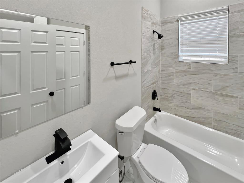 5530 Reiger Avenue, Unit 5528 Dallas, TX 75214 - Photo 19 of 40 a bathroom with a toilet a sink a mirror and bathtub
