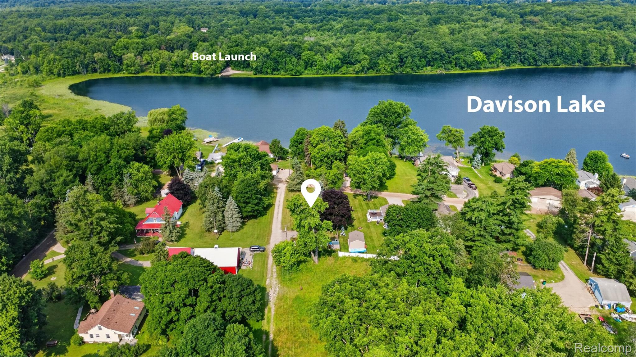 5977 Anglers Road Ortonville, MI 48462 - Photo 43 of 63 Aerial perspective showcasing a property surrounded by mature trees, with proximity to Davison Lake and a visible boat launch