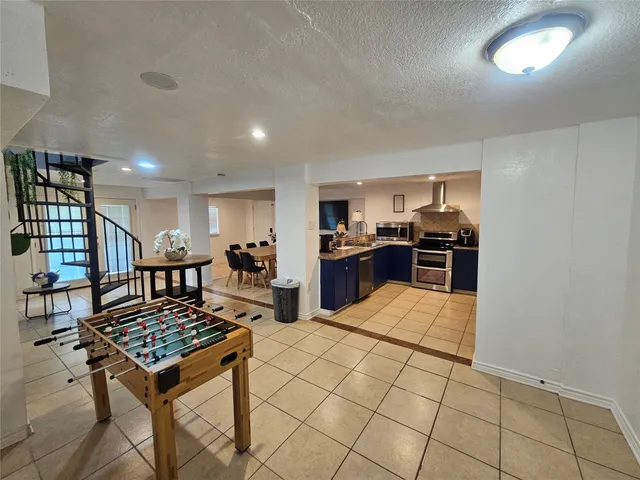 a kitchen with stainless steel appliances kitchen island granite countertop a refrigerator a stove a sink dishwasher and a dining table with wooden floor