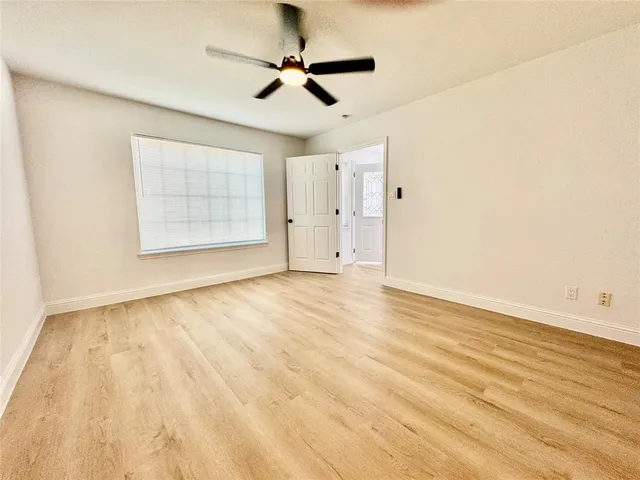 an empty room with wooden floor ceiling fan and windows