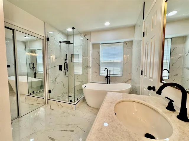 a bathroom with a tub sink shower and mirror